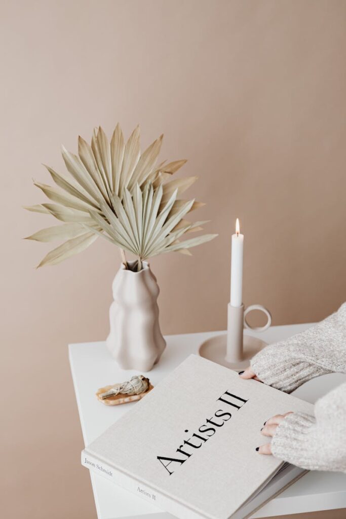 Elegant minimalist decor with dried palm, candle, and book, creating a warm and cozy atmosphere.