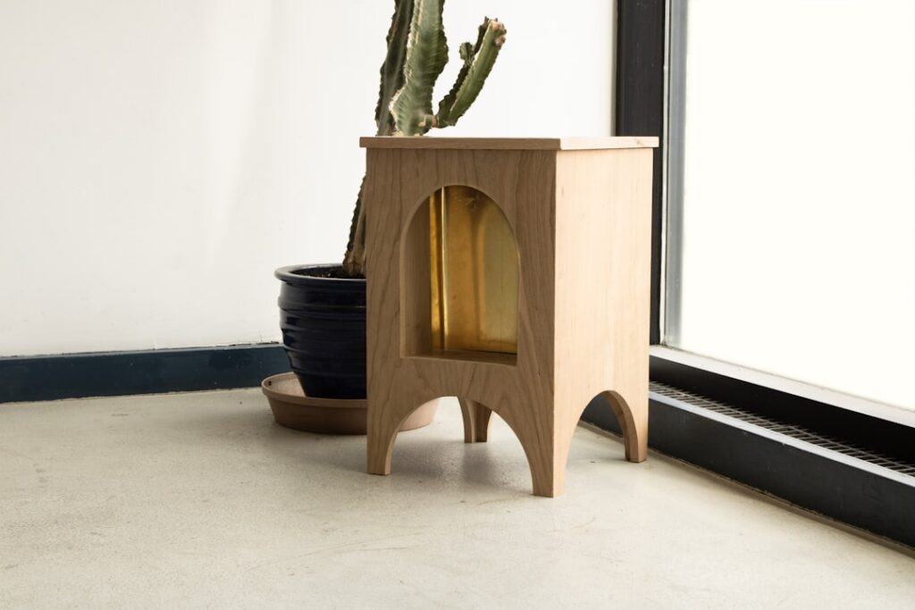 A photo of a side table set next to a blank wall and a window