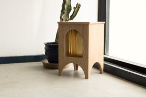 A photo of a side table set next to a blank wall and a window